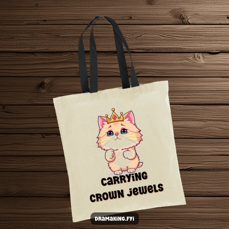 Funny tote bag depicts a fluffy cat wearing a crown, pointing at something sparkly, ideal for humorous cat enthusiasts.